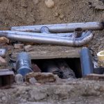 Tubulações e materiais dispostos em uma obra de instalação de rede subterrânea.