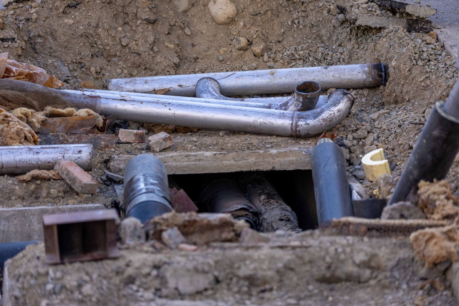 Tubulações e materiais dispostos em uma obra de instalação de rede subterrânea.