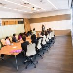 Grupo diverso de profissionais reunido em uma sala de conferências, participando de uma atividade de colaboração e formação.