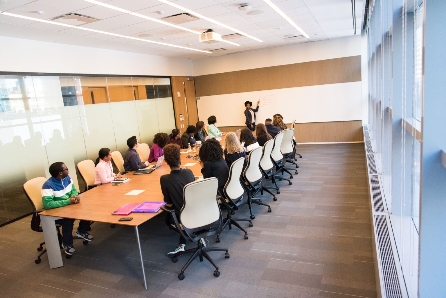 Grupo diverso de profissionais reunido em uma sala de conferências, participando de uma atividade de colaboração e formação.