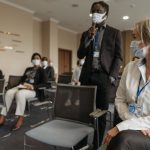 Profissionais de saúde usando máscaras participam de uma reunião em ambiente interno.