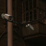 Câmeras de segurança instaladas em um poste, voltadas para uma área urbana.