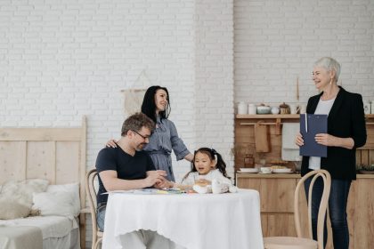 Família conversa à mesa com uma profissional da assistência social em ambiente doméstico.
