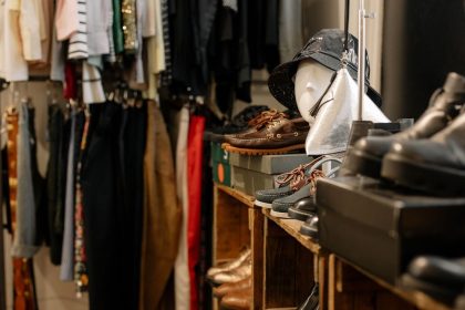 Interior de uma loja de roupas com peças, calçados e acessórios expostos.
