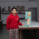 Estudante apresenta um modelo anatômico diante da turma em uma sala de aula.