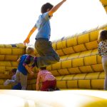 Crianças brincam em um castelo inflável colorido ao ar livre.